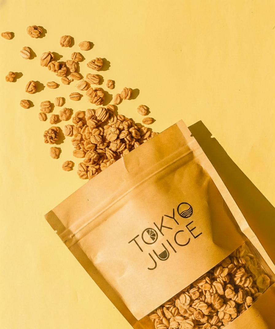 Open brown paper bag labeled 'Tokyo Juice' with scattered granola on a yellow background